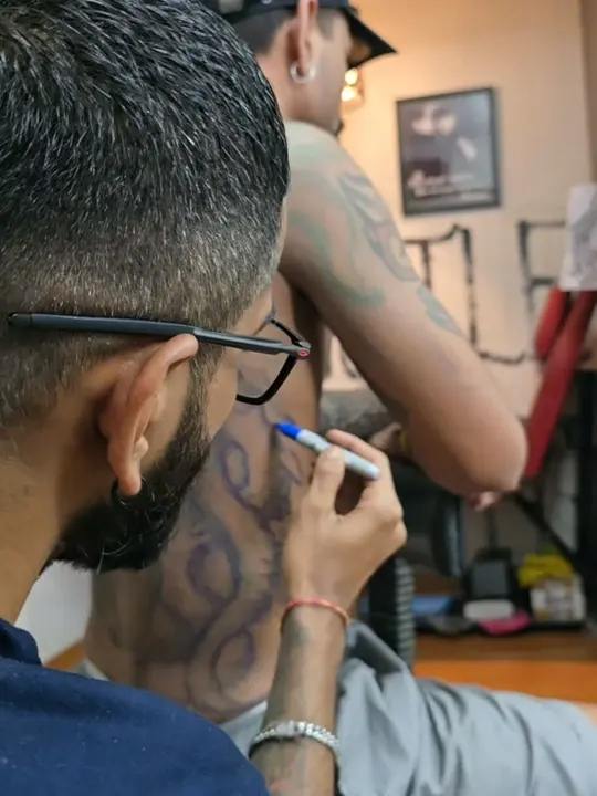 Shashi drawing a freehand design on a client's back